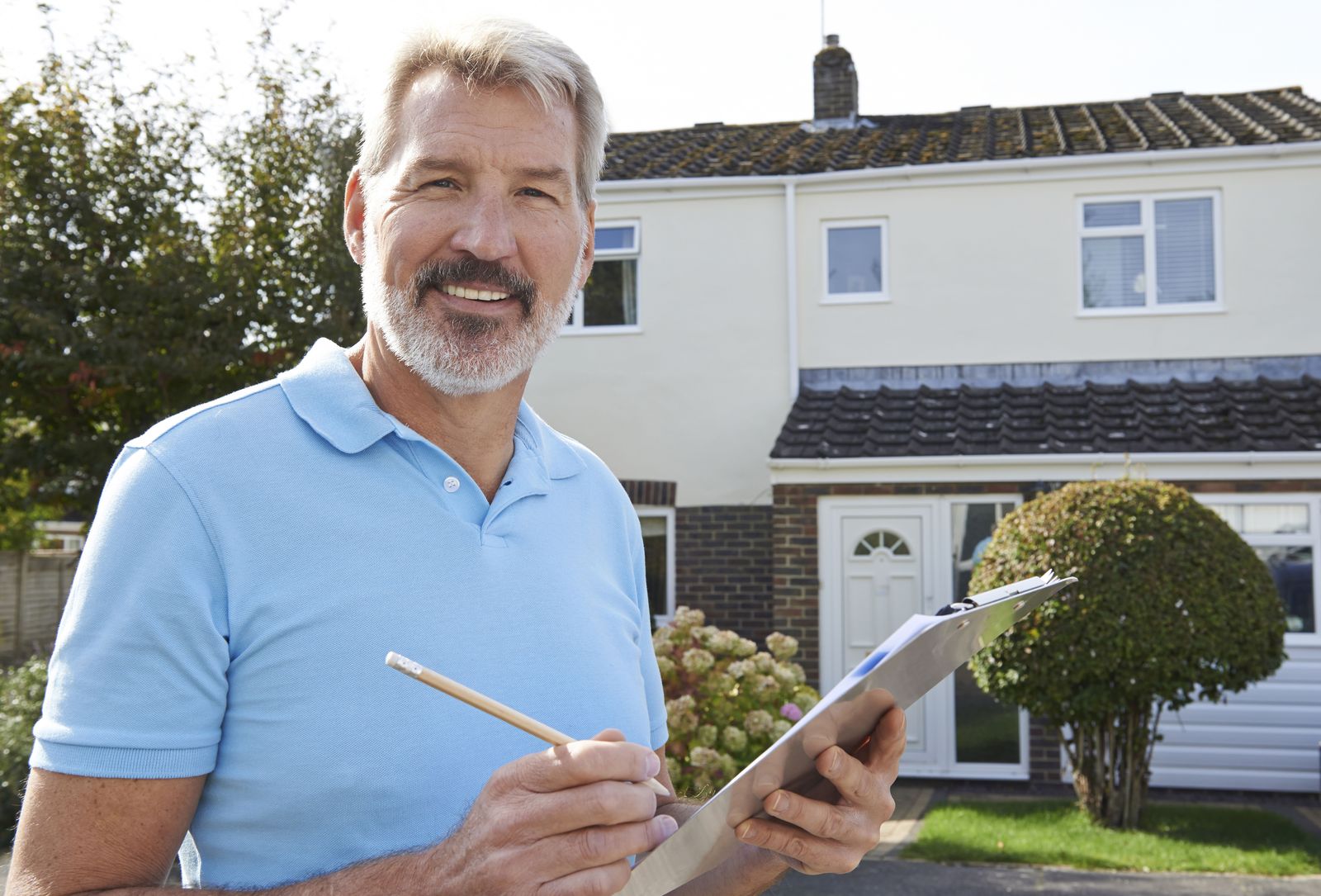 Contractor with a clipboard in front of a house; replace with a photo of Christian on a job
