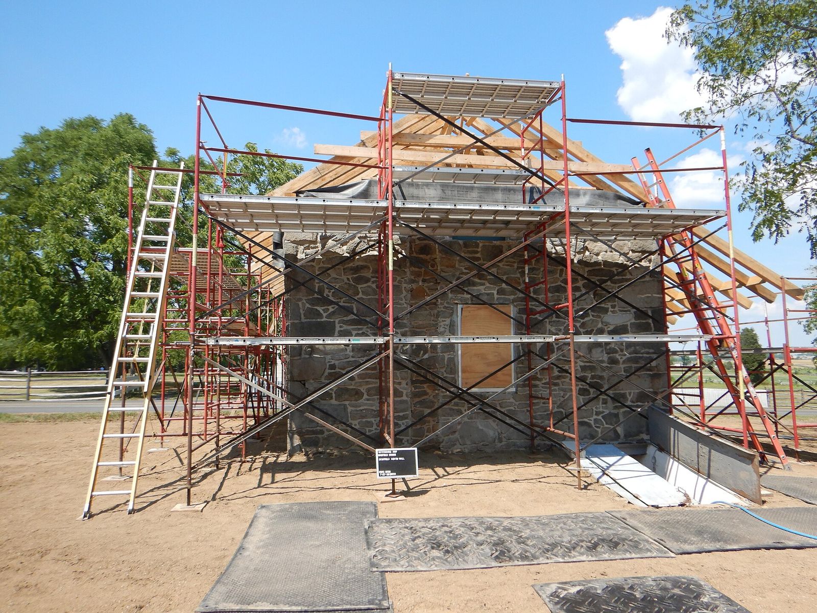 Scaffolding around a stone house during a steep roof replacement